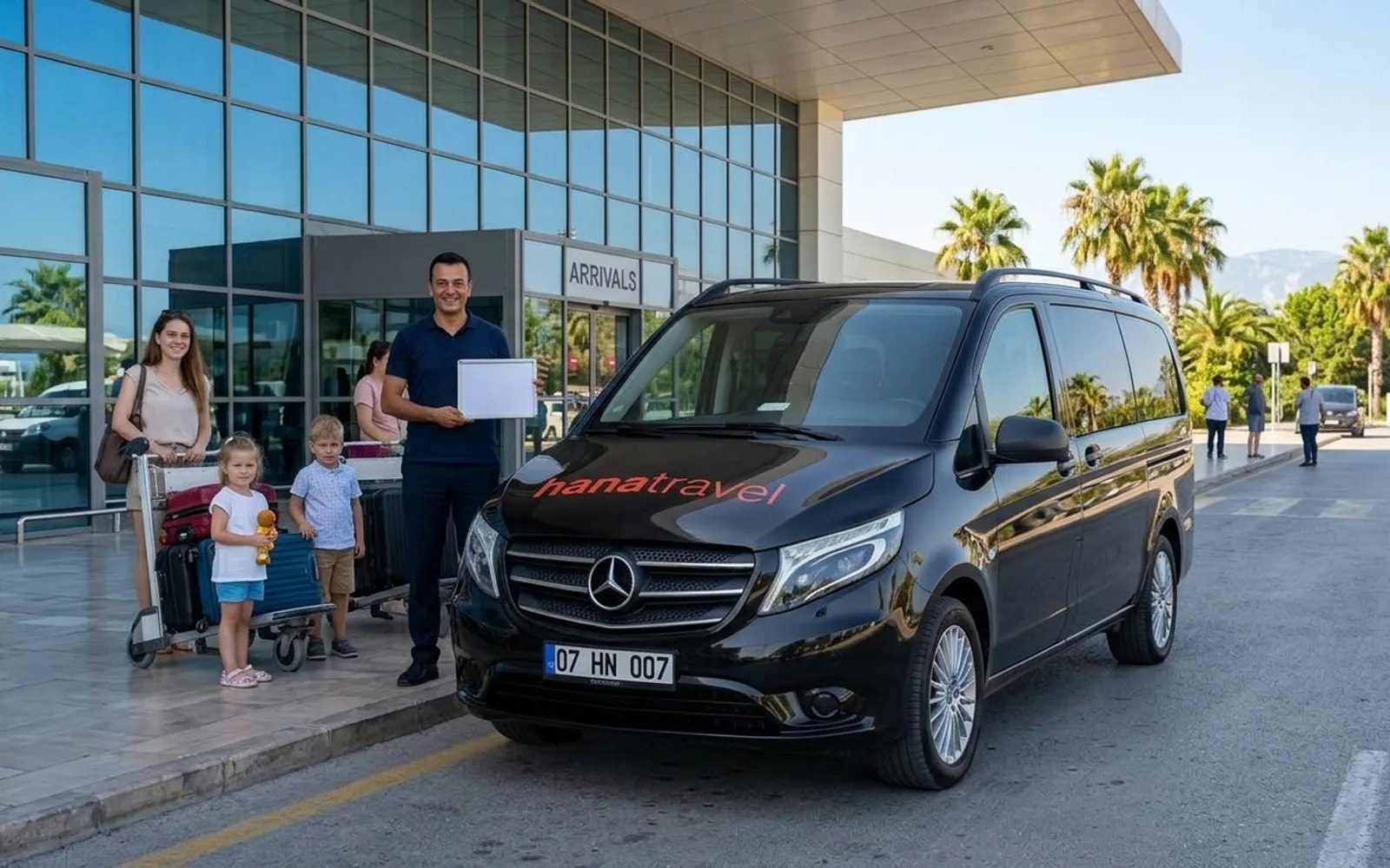 Your name on the board, the car at the kerb Driver with a name board greeting a family beside the black Hana Travel Vito outside Antalya Airport arrivals — Antalya airport transfer