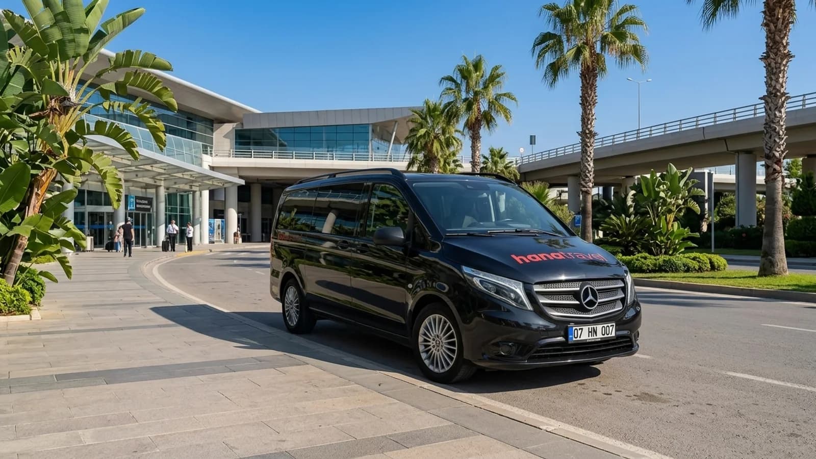 Antalya Airport Transfer: How Private Rides Work A black transfer van parked near palm trees outside Antalya Airport for an Antalya airport transfer.